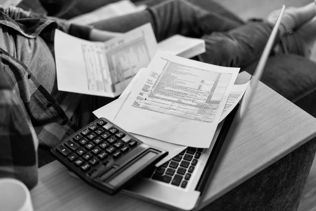 Calculatrice et documents posés sur un ordinateur portable.