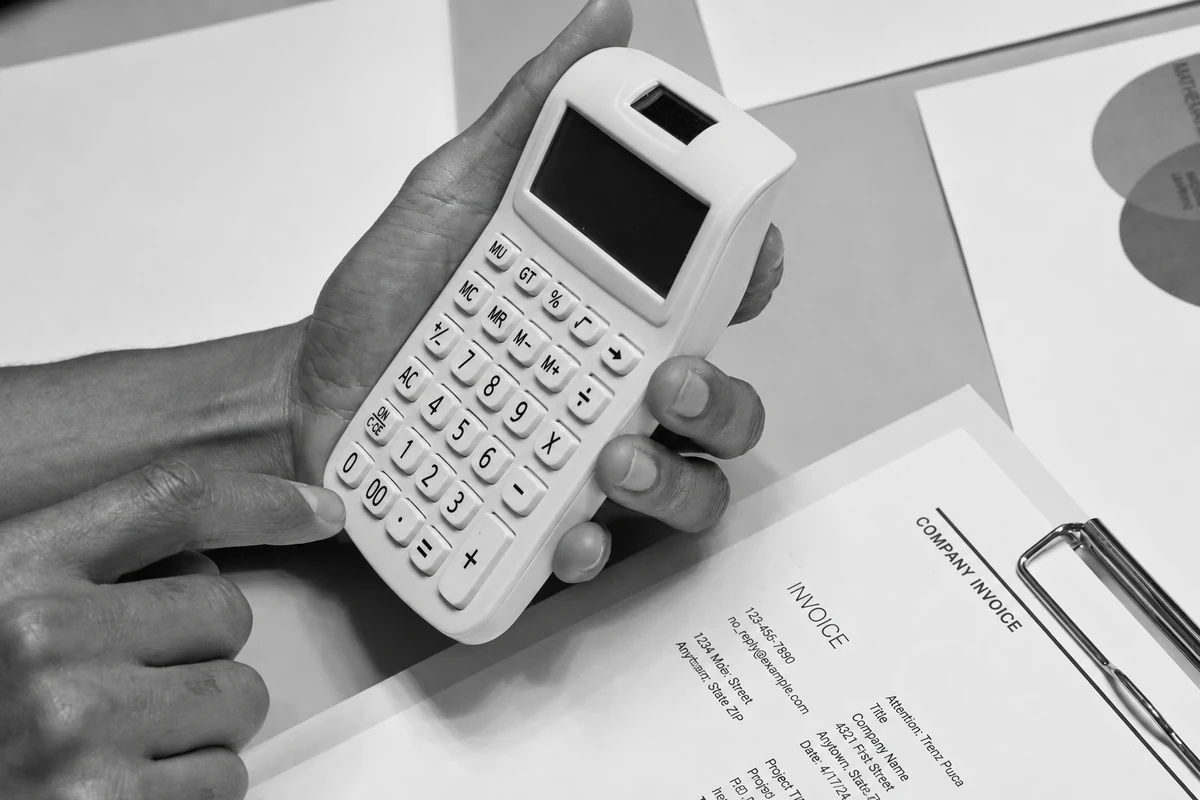 Mains utilisant une calculatrice devant une facture.